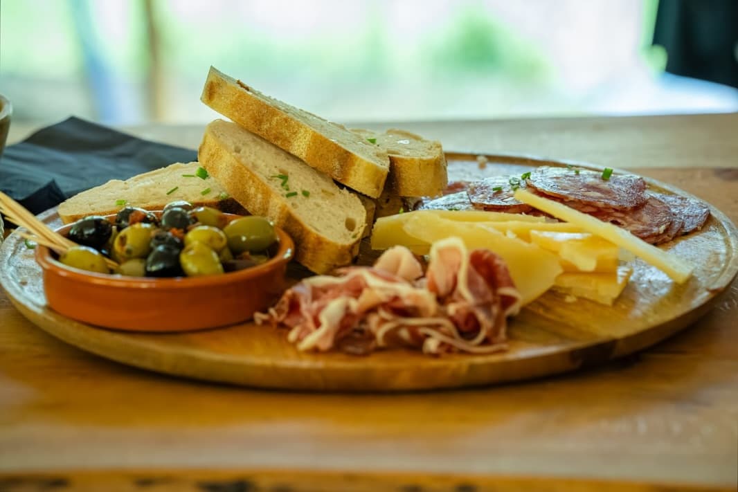 Houten plank met brood, olijven, kaas en charcuterie