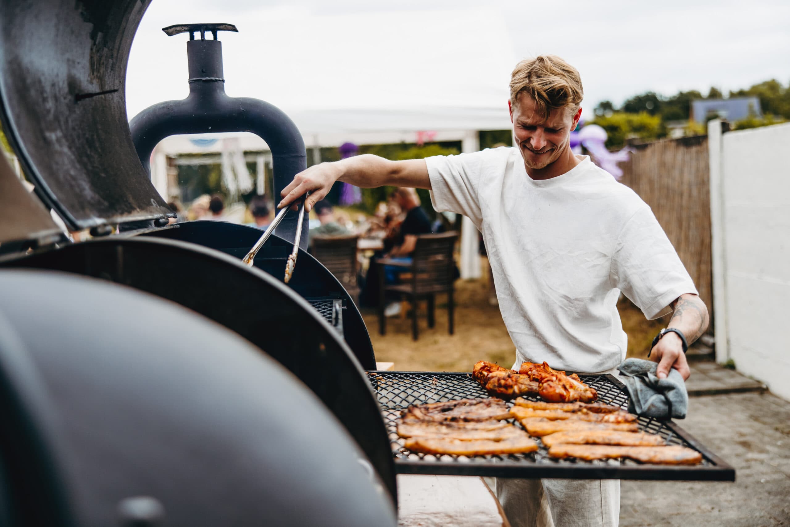 Lachende chef grilt vlees op de smoker tijdens een feest