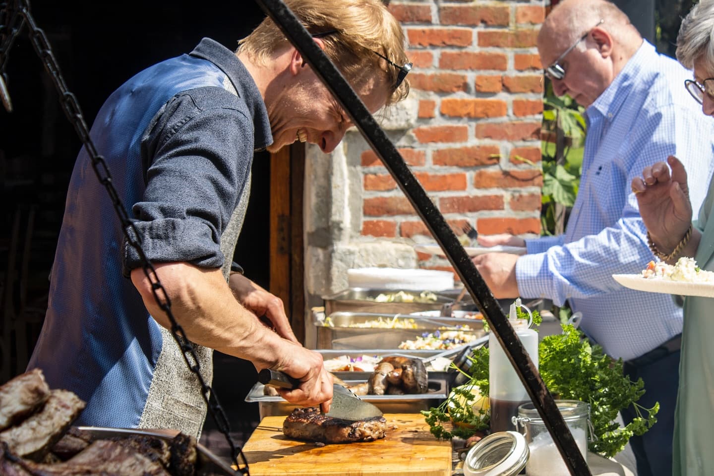 Chef snijdt vlees terwijl een gast wordt bediend op een feest
