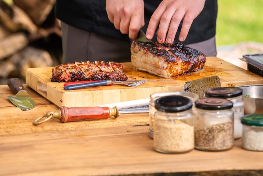 Ribben en buikspek worden aangesneden naast potjes met kruiden