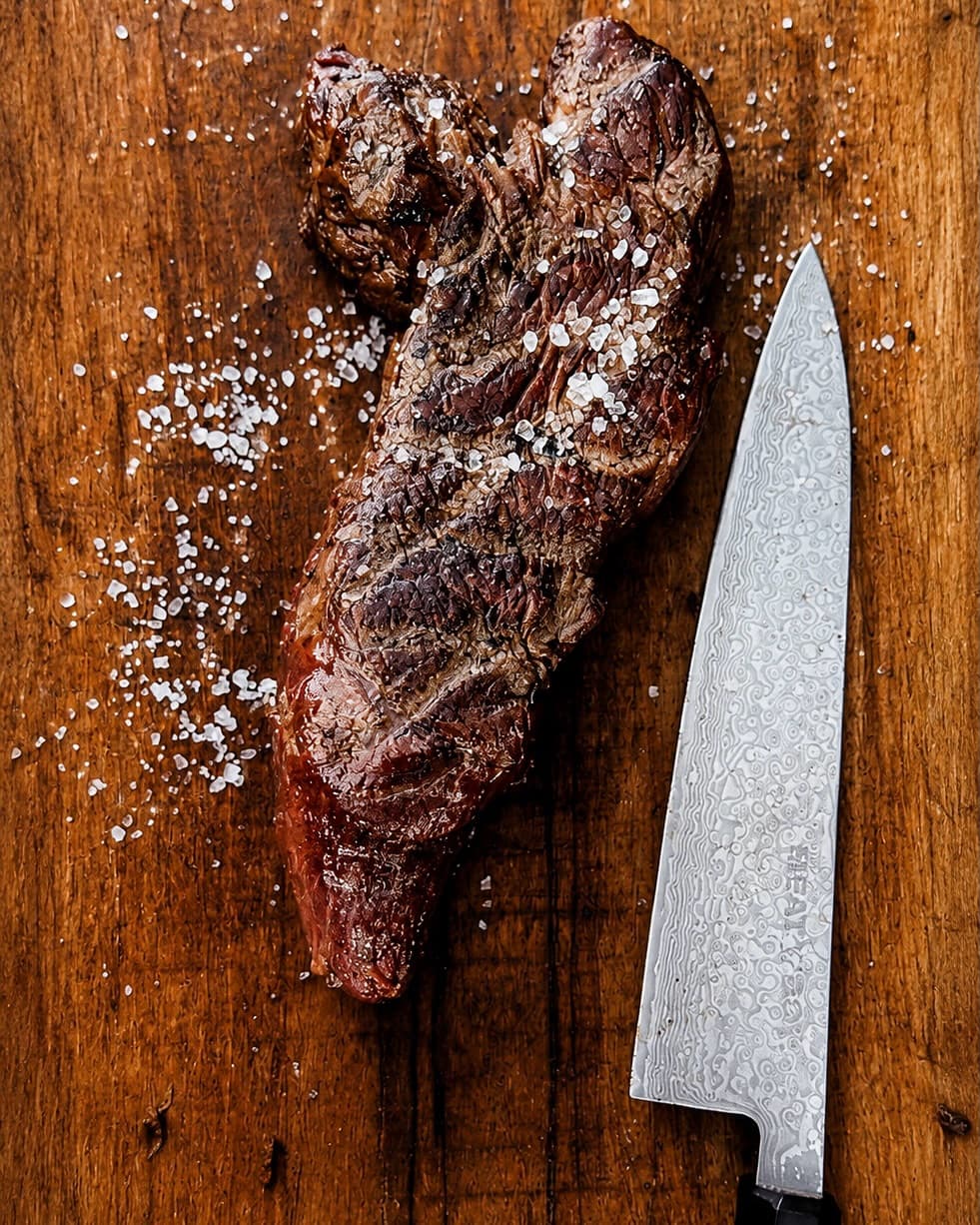 Gegrilde steak met zout en damascus mes op een houten snijplank